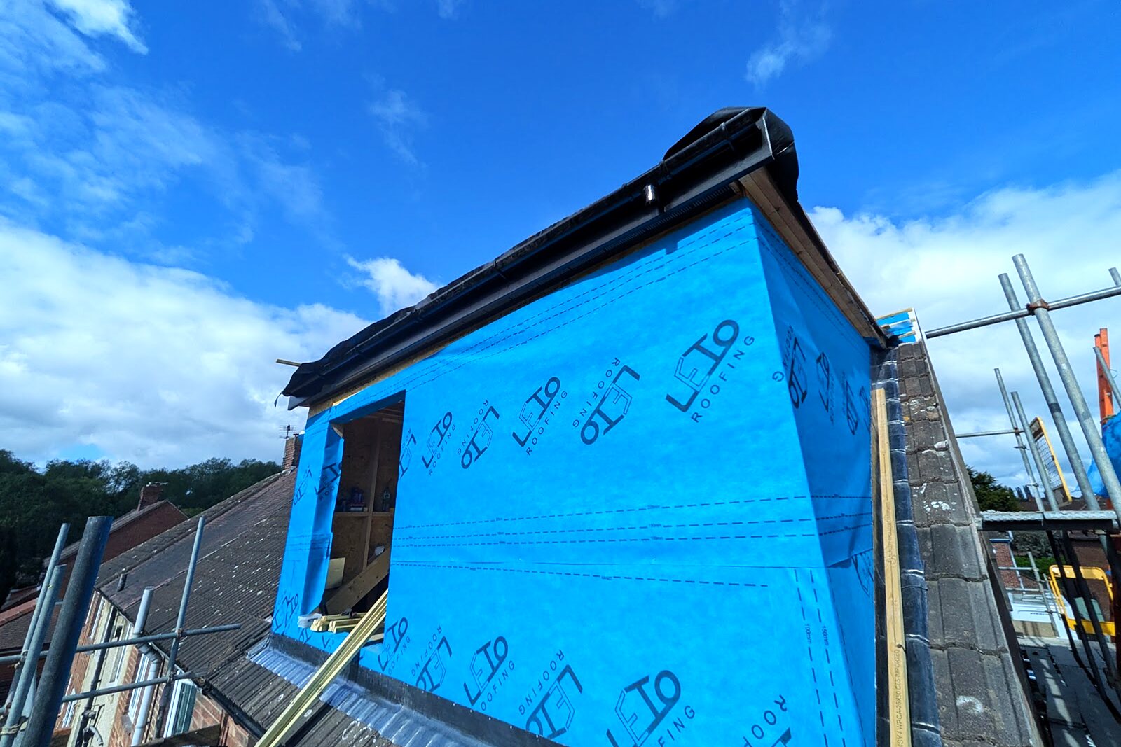 Dormer wrapped in blue breather membrane with a new flat roof edge detail