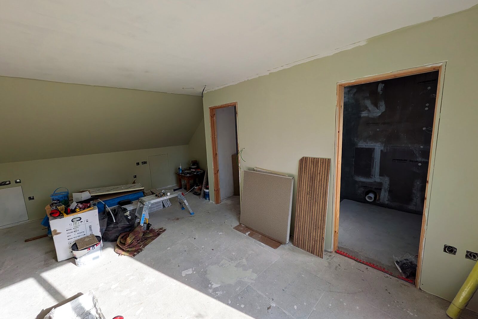 Plastered and decorated loft room with a new door and sloping ceiling