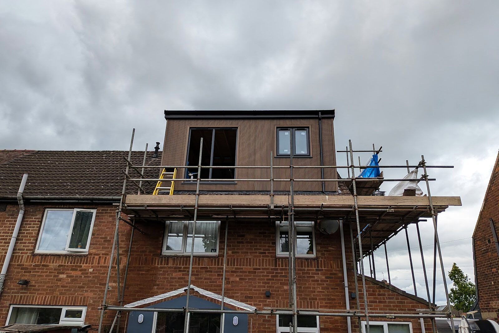 Dormer clad in dark vertical timber-effect boards with scaffolding still up