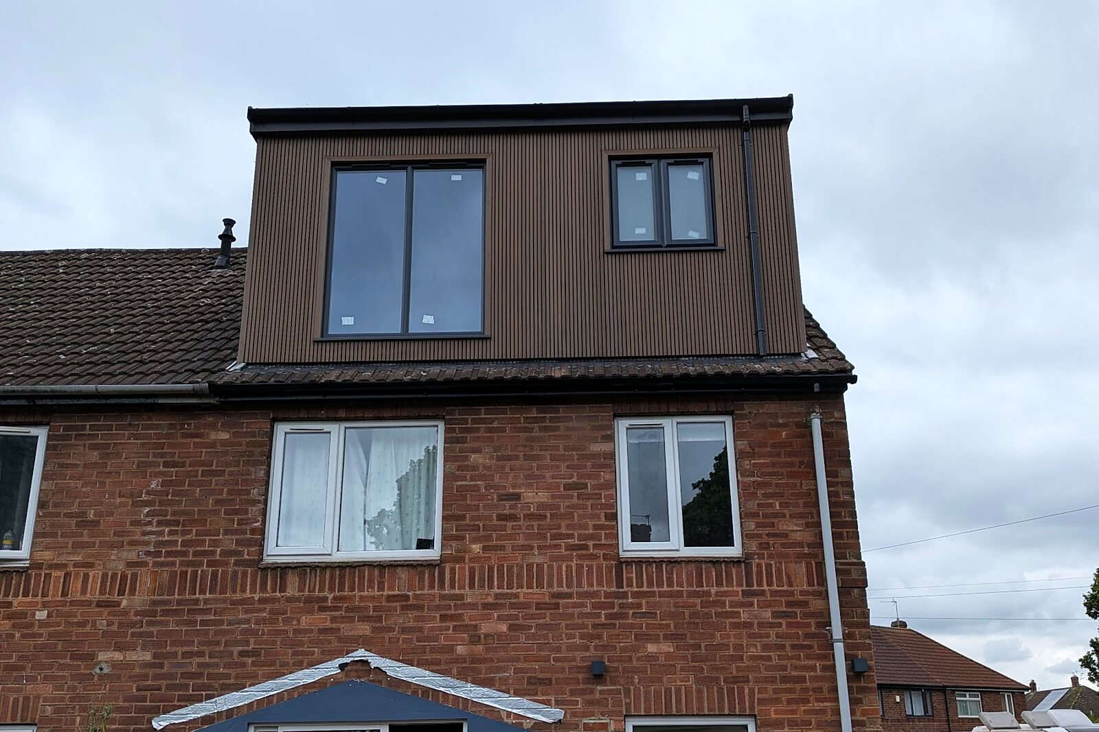 Completed dormer loft conversion with dark timber cladding on a brick semi-detached house in Acomb, York