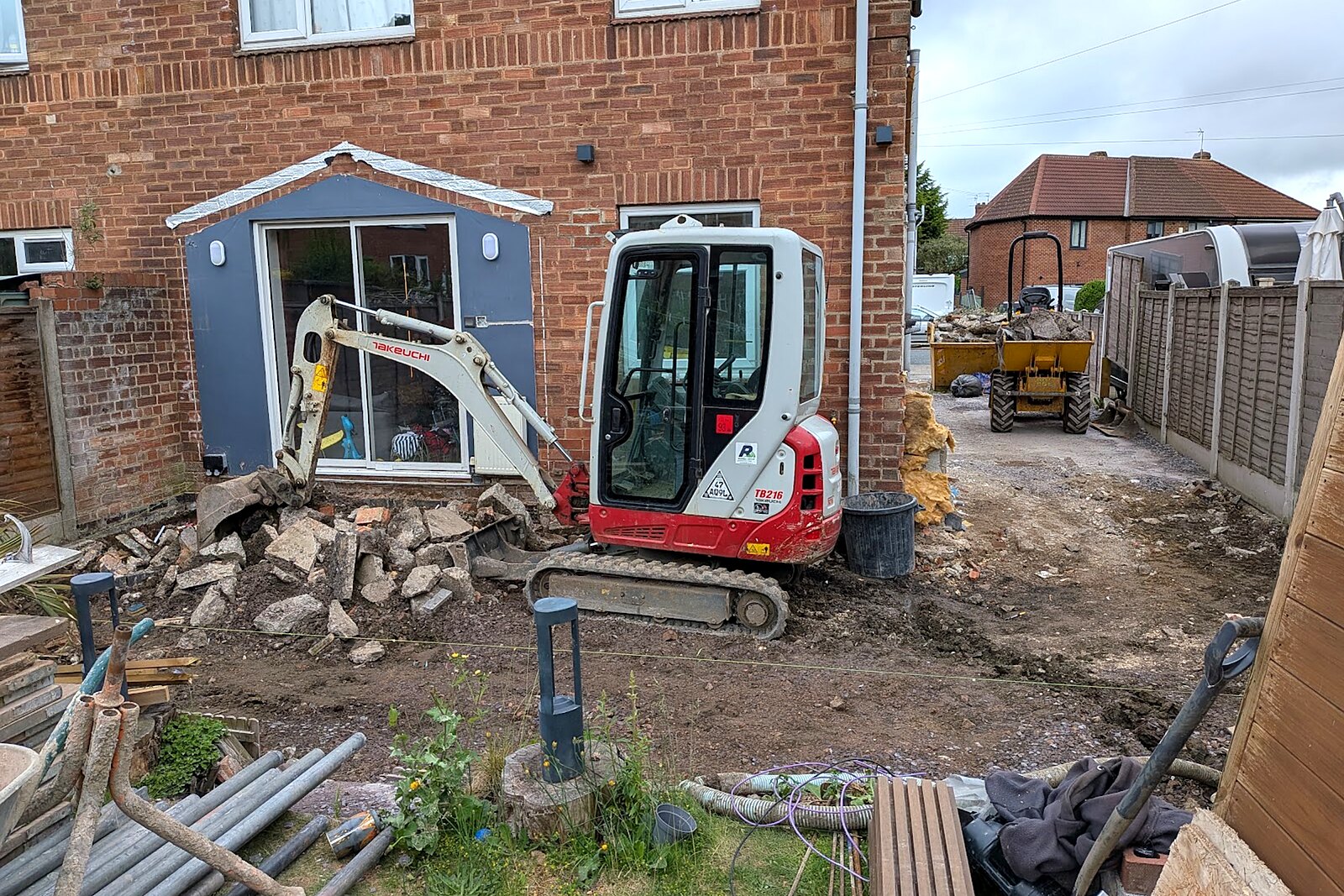 Mini digger clearing the rear garden of a semi-detached house ready for an extension