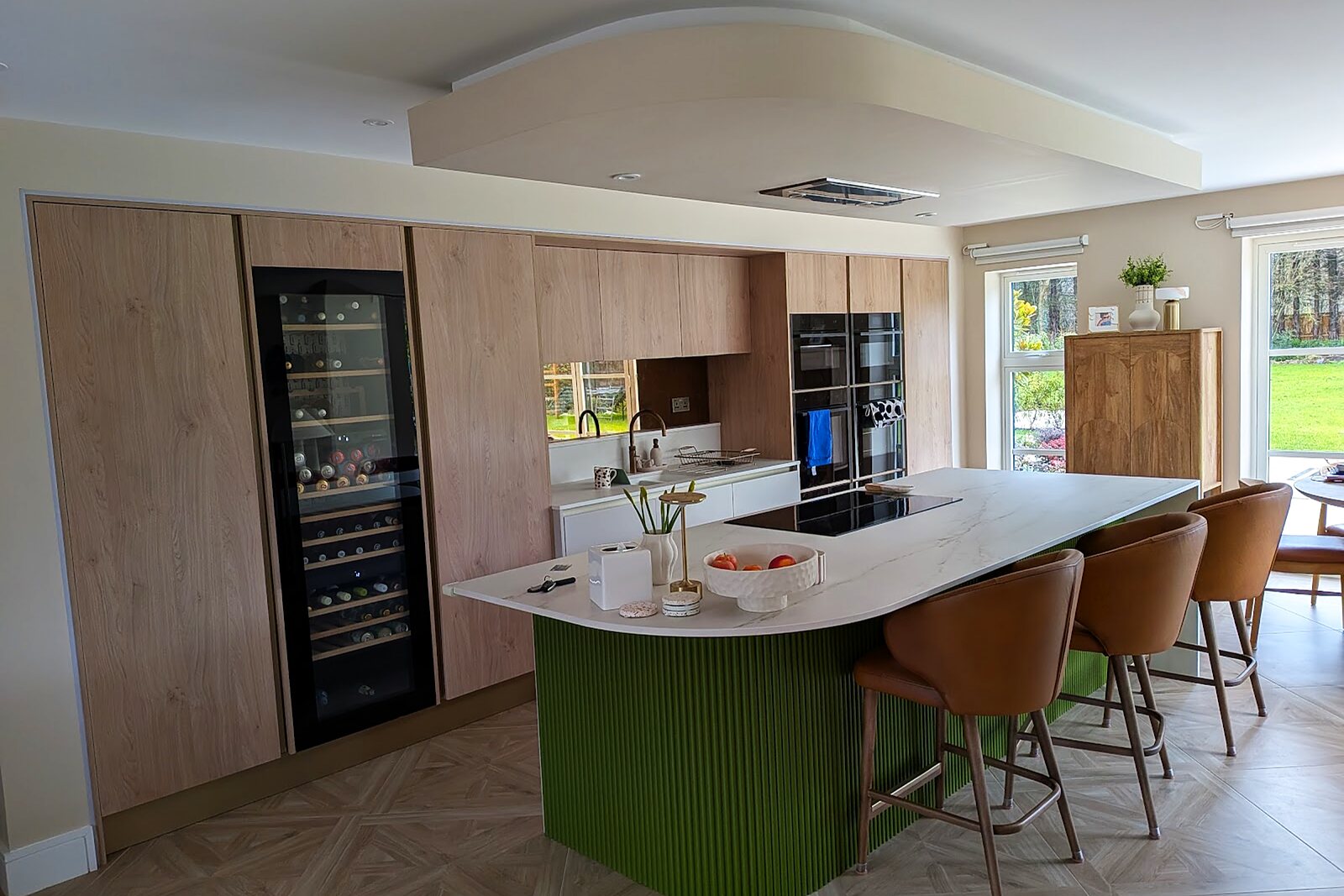 Open-plan kitchen with a green island, stone worktop and integrated appliances in a renovated house in Fulford, York